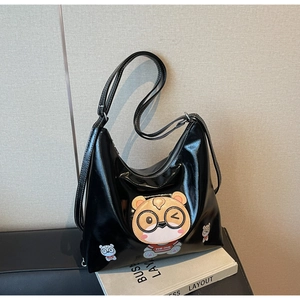 Detail of glossy black tote bag featuring a cute cartoon bear embroidery patch