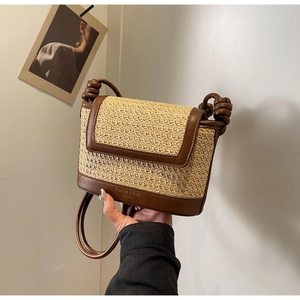 Detail of hand-woven straw crossbody bag with brown leather trim and retro printed base