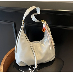 Détail du sac demi-lune blanc crème avec chaîne en acrylique rose et pendentif tissé