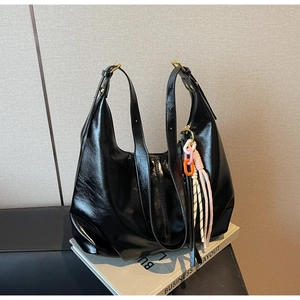Détail du sac hobo en similicuir noir brillant avec boucle dorée et breloque chaîne