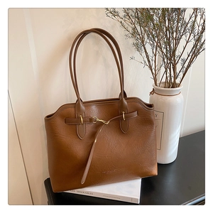 Detail of vintage brown leather tote bag with crinkled texture and gold metal buckle