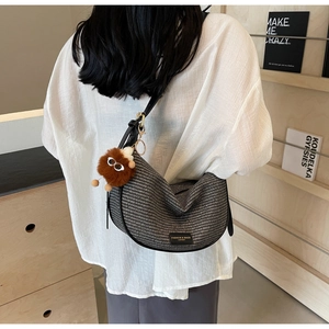 Detail of woven hobo bag with leather strap and plush monster charm worn by model