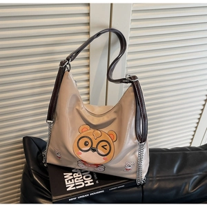 Detail of beige tote bag with cute cartoon bear print and stylish metal chain strap