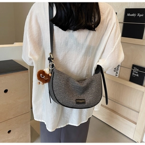 Detail of hobo crossbody bag in black and white weave with plush charm and leather strap