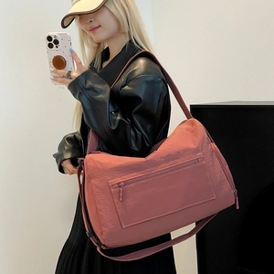 Nahaufnahme der ziegelroten Nylon-Reisetasche mit Reißverschlussfach und Schultergurt