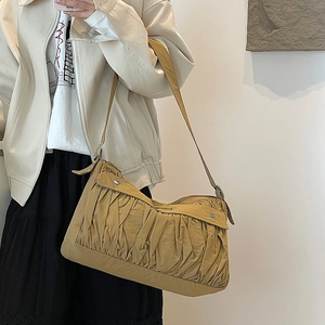 Detail showing mustard yellow pleated fabric texture and side metal buckle of the bag