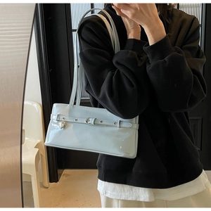 Detail of light blue patent leather underarm bag with metal heart pendant decoration
