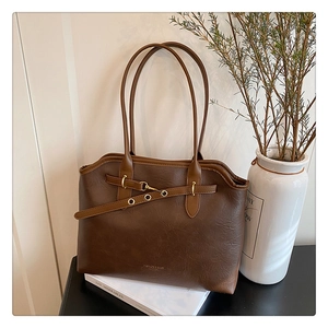 Detail of dark brown leather tote bag with vintage metal buckles and leather texture