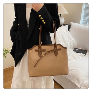 Detailed view of spacious light brown leather tote bag with elegant dark handles and gold hardware