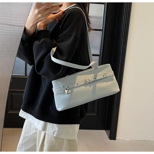 Mirror selfie showing a light blue baguette shoulder bag with a metal heart pendant