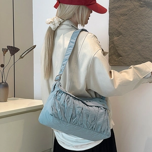 Detailed view of grey blue pleated shoulder bag worn by model in minimalist setting
