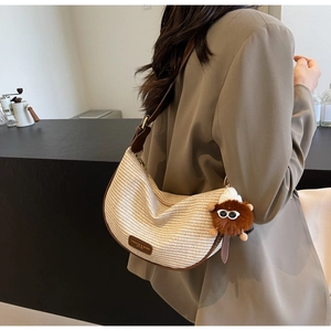 Detail of woven crescent bag with brown leather trim and cute monster charm detail