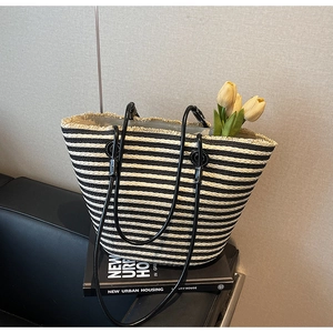 Close-up of black and white striped woven tote bag with fringe edge and leather straps