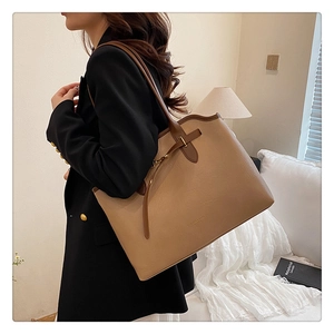 Close-up of the textured khaki leather tote bag with elegant metal buckle and strap details