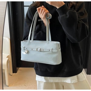 Detail of light blue patent leather shoulder bag with silver heart charm and buckle strap