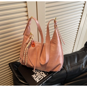Détail d'un sac cabas rose avec un pendentif à pompon tissé coloré et une boucle métallique