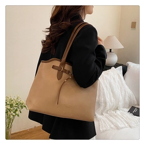 Close-up of khaki tote bag featuring buckle detail and tassel on high-quality leather