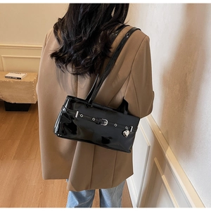 Detail of glossy black patent leather shoulder bag with silver heart charm and metal eyelets