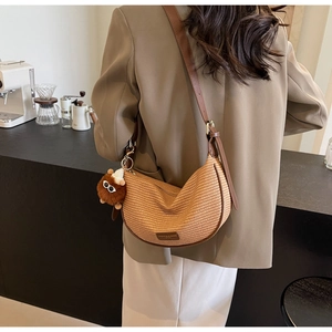 Khaki hobo bag with leather strap and plush doll charm in a cozy cafe setting