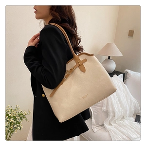 Detail view of cream leather tote bag with brown straps and pebble grain texture