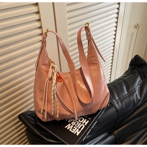 Détail d'un sac Hobo rose poudré avec un charme de corde tressée sur cuir haut de gamme