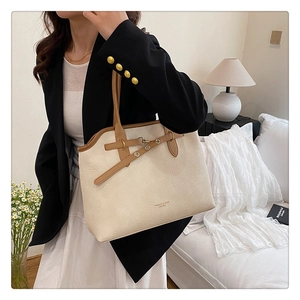 Detail of minimalist cream tote bag with brown straps and elegant gold hardware accents