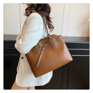 Detail of dark brown tote bag with metal buckle and leather fashion logo branding