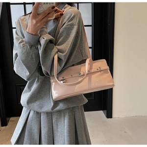 Chic pink patent leather underarm bag with metal heart charm shown on a female model