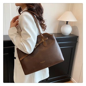 Detail of coffee brown leather tote with gold buckle and embossed fashion lettering