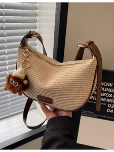 Chic beige straw hobo bag with brown leather strap and monster charm decoration