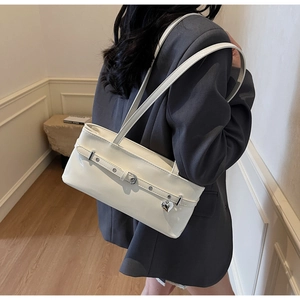 Detail of cream white faux leather baguette bag with silver heart pendant on a model