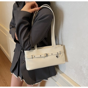 Detail of cream white patent leather shoulder bag with decorative silver heart charm