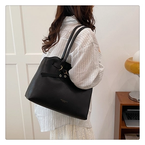 Close-up of black tote bag with lychee texture and gold fashion lettering on the side
