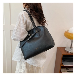 Detail of black textured tote bag with golden hardware and fashion leather branding