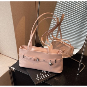 Detailed view of pink patent leather handbag with silver heart pendant and buckle strap