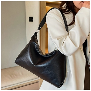 Detail of a large black hobo shoulder bag with soft textured leather on a model