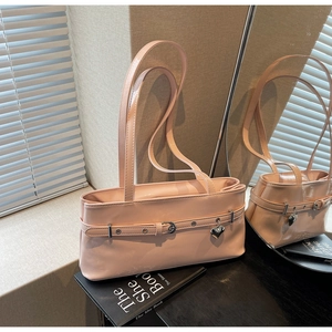 Detail of pink glossy shoulder bag featuring metal buckle strap and a heart-shaped charm
