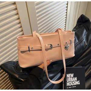 Close-up of pink patent leather shoulder bag with silver heart pendant and metal buckle