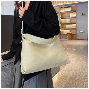 Detail of creamy white leather tote bag featuring soft pleated texture and wide strap