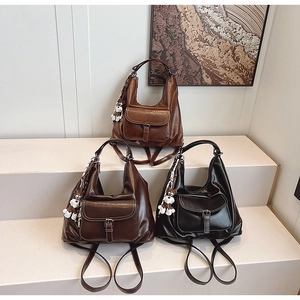 Close-up of retro PU leather backpacks in brown and black with plush charm details