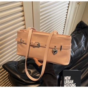 Detail of pink patent leather shoulder bag with decorative buckle and heart pendant