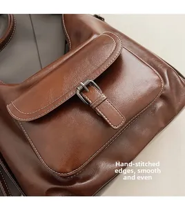 Detail of hand-stitched edging and bronze buckle on a brown vintage leather tote bag