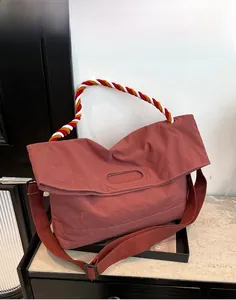 Détail du fourre-tout rose poudré avec poignée tressée multicolore et large bandoulière