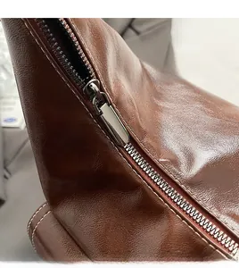 Macro detail of smooth dark silver metal zipper on premium brown lychee textured leather bag