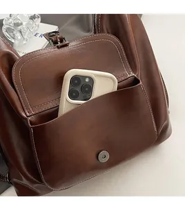Detail of dark brown leather tote with magnetic front pocket and white contrast stitching
