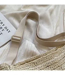 Dettaglio della tracolla regolabile beige e trama a uncinetto della borsa in paglia