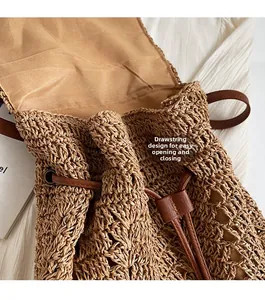 Detail of the drawstring closure and faux leather buckle on a stylish woven straw backpack
