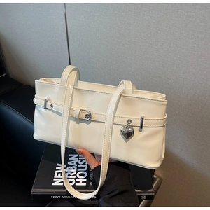 Detail of glossy cream patent leather shoulder bag with silver buckle and heart charm