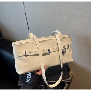Detail view of a cream minimalist underarm bag with silver heart charm and metal buckle