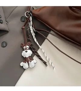 Detail of a leather Schnauzer dog charm with woven ropes on a brown tote bag